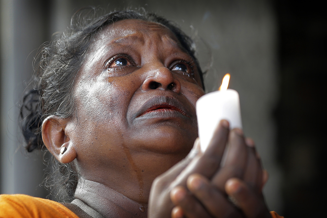 A Sri Lankan roman catholic woman prays during a three minute nationwide silence observe to pay homage to the victims of Easter Sunday's blasts outside St. Anthony's Shrine in Colombo, Sri Lanka, Tuesday, April 23, 2019. A state of emergency has taken effect giving the Sri Lankan military war-time powers not used since civil war ended in 2009. Police arrested 40 suspects, including the driver of a van allegedly used by suicide bombers involved in deadly Easter bombings. (AP Photo/Eranga Jayawardena)